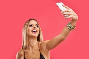bellissimo adulto donna in posa al di sopra di rosa sfondo con smartphone foto