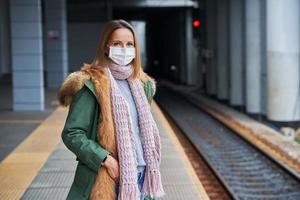 adulto donna a treno stazione indossare maschere dovuto per covid-19 restrizioni foto