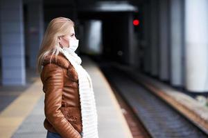 adulto donna a treno stazione indossare maschere dovuto per covid-19 restrizioni foto