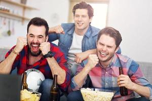 contento maschio amici applauso e Guardando gli sport su tv foto