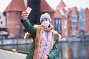 donna indossare viso maschera e assunzione autoscatto nel il città foto