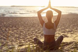 silhouette giovane donna a praticare yoga sulla spiaggia al tramonto foto