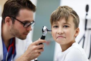 avvicinamento di maschio medico l'esame ragazzi orecchio con un otoscopio foto