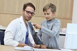 poco ragazzo nel clinica avendo un' verifica con pediatra foto