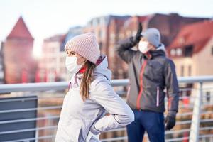 adulto coppia jogging nel il città nel maschere durante lockdown foto