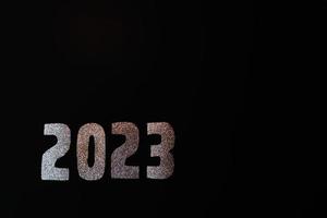 contento nuovo anno 2023. d'oro numeri su un' nero sfondo con luccichio foto
