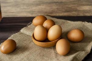 Marrone gallina uova nel un' ciotola e su il tavolo. fresco pollo Marrone uova nel su un' di legno sfondo. salutare mangiare concetto foto