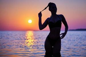 silhouette di sexy donna in posa a Alba a il spiaggia foto