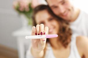 contento coppia con gravidanza test nel Camera da letto foto