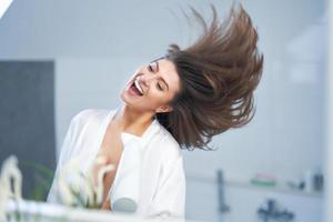 giovane simpatico brunetta donna nel il bagno cura dei capelli foto