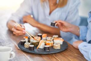 simpatico Due adulto ragazze nel il Casa mangiare Sushi foto