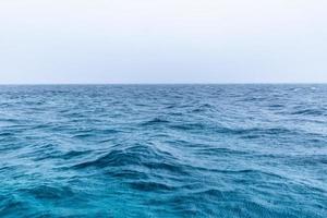 pioggia al di sopra di il tempestoso mare, blu oceano acqua e pioggia gocce. infinito mare Visualizza orizzonte, nebbia e nebbioso rilassante umore. astratto mare foto