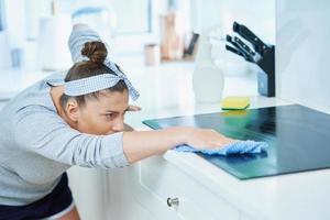 giovane donna pulizia sporco nel il cucina foto
