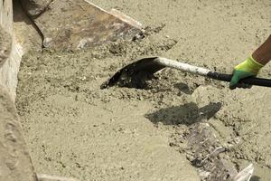 pala e cemento. pala nel mani di lavoratore. cemento miscela rovesciato su strada. pulizia di edificio Materiale. foto