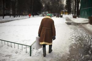 russo pensionato passeggiate giù strada nel inverno. vecchio donna nel Russia. anziano uomo di orientale Europa. foto