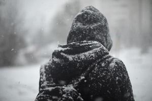 uomo al di fuori nel nevicata. nero Abiti nel neve. tipo è in piedi nel mezzo di cittadina. foto