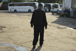 uomo passeggiate attraverso industriale la zona. autobus parcheggio. parcheggio guardia. foto