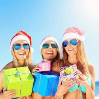 gruppo di ragazze nel Babbo Natale cappelli avendo divertimento su il spiaggia foto