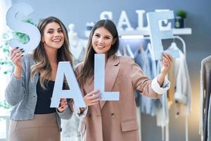 Due ragazze su shopping Tenere vendita percentuale cartello. foto