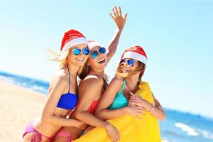 gruppo di ragazze nel Babbo Natale cappelli avendo divertimento su il spiaggia foto