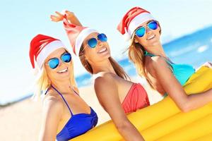 gruppo di ragazze nel Babbo Natale cappelli avendo divertimento su il spiaggia foto