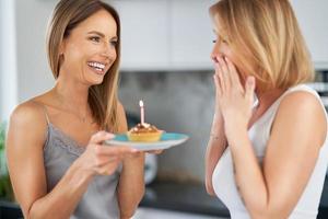 simpatico Due adulto ragazze nel il Casa con compleanno torta foto