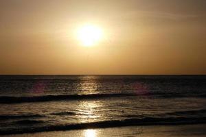 sole ambientazione al di sopra di il mare, tramonto nel autunno su il spiaggia di zahara de los intona, Cadice, andalusia, Spagna foto