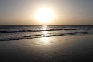 sole ambientazione al di sopra di il mare, tramonto nel autunno su il spiaggia di zahara de los intona, Cadice, andalusia, Spagna foto