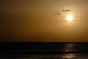 sole ambientazione al di sopra di il mare, tramonto nel autunno su il spiaggia di zahara de los intona, Cadice, andalusia, Spagna foto