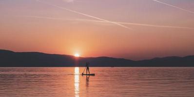 sportivo giovane uomo su cenare pagaia tavola andando per il mare a tramonto. foto