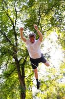 giovane uomo equilibratura e salto su slackline. uomo a passeggio, salto e equilibratura su corda nel parco. foto