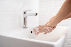 donna lavaggio sua mani nel il bagno a casa foto