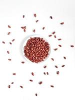 asciutto rosso fagioli su un' bianca piatto, circondato di sparpagliato asciutto rosso fagioli su un' bianca sfondo. superiore Visualizza foto
