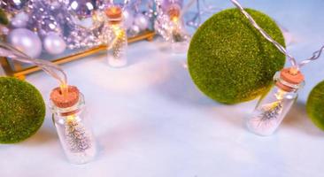 Magia ghirlanda - giocattolo Natale alberi nel bicchiere barattoli e verde erba palle, su un' blu sfondo. un' bicchiere cofanetto con argento ornamenti. foto