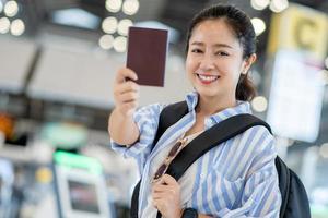 contento asiatico donna mostrando passaporto nel mano nel internazionale aeroporto su fine settimana viaggio foto