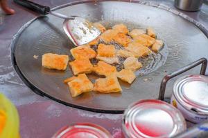 roti Impasto su un' caldo padella è cucinando. con condimenti su il tavolo. foto