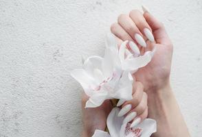 mani di un' giovane donna con bianca manicure su Chiodi foto