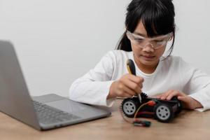 gli studenti asiatici imparano a casa a codificare auto robot e cavi di schede elettroniche in stelo, vapore, matematica ingegneria scienza tecnologia codice informatico in robotica per bambini concetto. foto