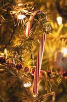 caramella canna sospeso su un' Natale albero con morbido luci foto