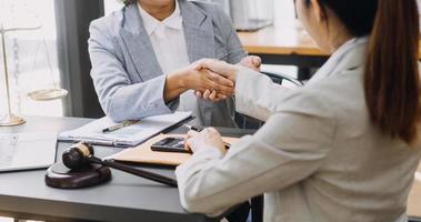 concetto di giustizia e diritto. giudice maschio in un'aula di tribunale con il martelletto, lavorando con computer e tastiera docking, occhiali, sul tavolo alla luce del mattino foto