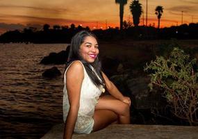 bello giovane brasiliano ragazza con un' bellissimo Sorridi a il parco a tramonto foto