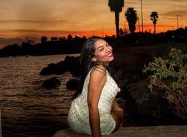 bello giovane brasiliano ragazza con un' bellissimo Sorridi a il parco a tramonto foto