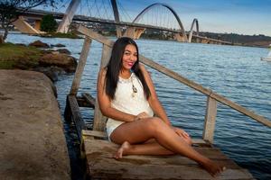 bello giovane brasiliano ragazza con un' bellissimo Sorridi a il parco con il jk ponte nel brasiliana, nel il sfondo foto