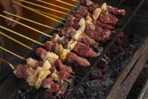 saziare kambing o satay capra, agnello, agnello o carne capra satay con carbone ingrediente su rosso fuoco grigliate di le persone. tradizionale satay a partire dal Yogyakarta, Giava, Indonesia cucinando satay foto