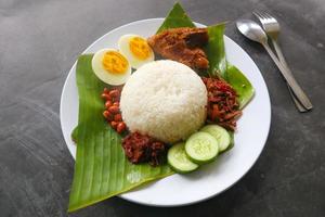 nasi lemak, è tradizionale malese fatto bollito uova, fagioli, acciughe, chili salsa, cetriolo. a partire dal piatto servito su un' Banana foglia foto