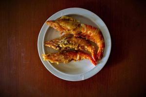 fritte gamberetto servito con pomodori, scalogno, aglio con taglio tavola su nero sfondo foto