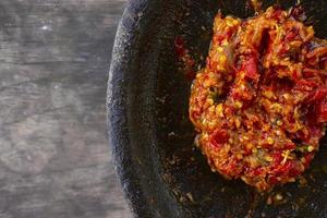 fresco Sambal servito su pietra mortaio cobek. Sambal è tradizionale salsa a partire dal Indonesia fatto a partire dal chili foto