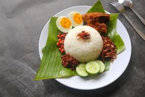 nasi lemak, è tradizionale malese fatto bollito uova, fagioli, acciughe, chili salsa, cetriolo. a partire dal piatto servito su un' Banana foglia foto