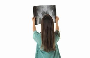 giovane femmina medico guardare a il raggi X immagine. isolato su bianca foto