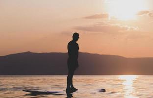 bello sportivo uomo è kayak su tramonto foto